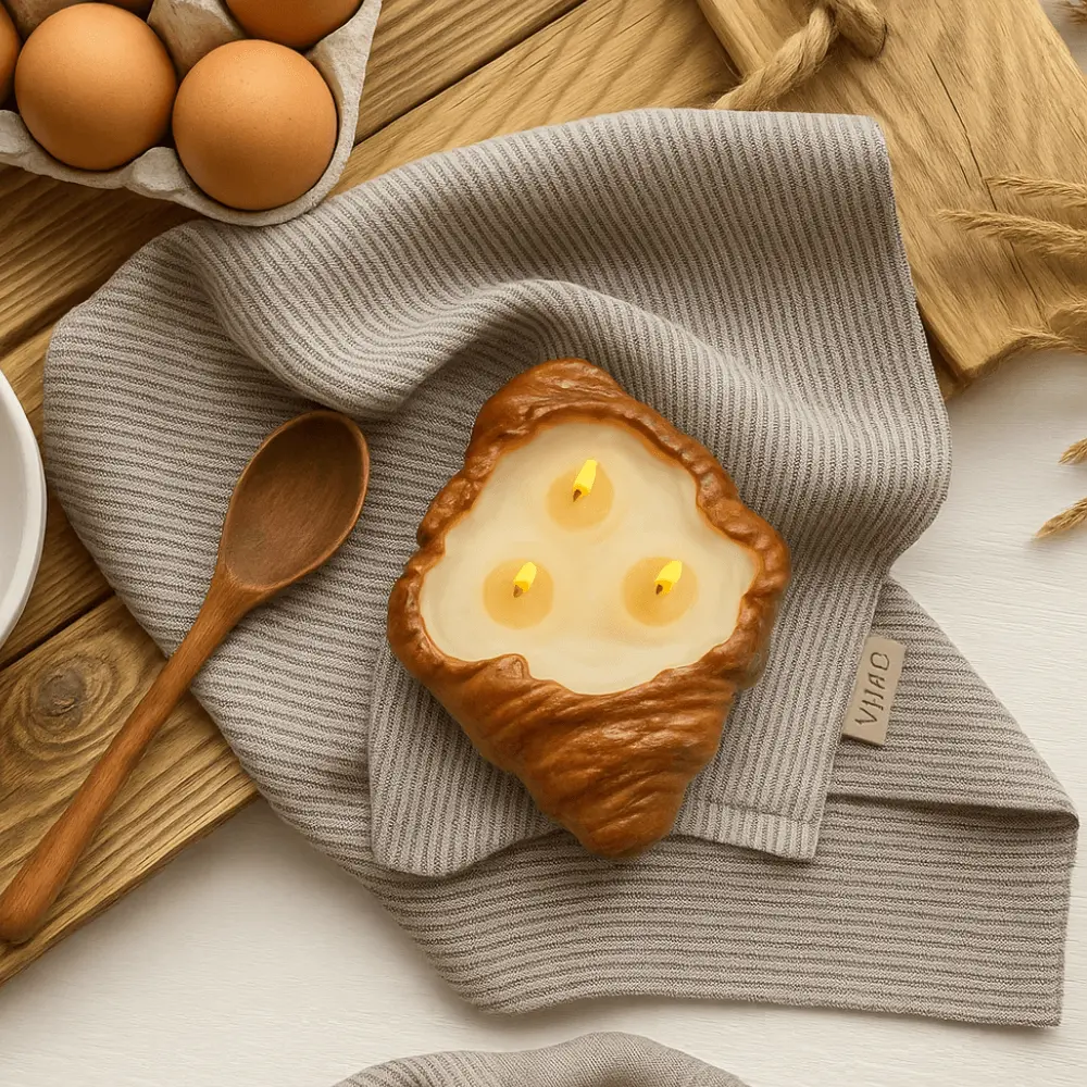 Realistic dessert-inspired soy candle shaped like a croissant with bakery and coffee scents