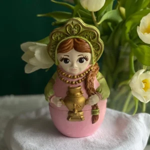Handmade decorative matreshka doll-shaped scented candle in traditional style, elegant gift for International Women’s Day, March 8 candle with feminine design and spring floral background.