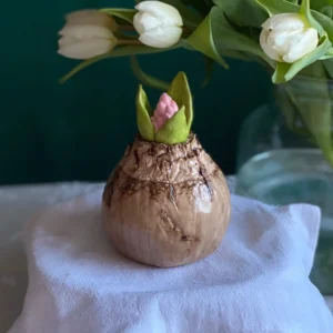 Handmade spring bloom candle shaped like a flower bulb with pink blossom and green leaves, decorative scented candle for International Women’s Day, elegant March 8 gift with fresh floral decor.