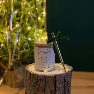 Christmas countdown candle with a December calendar label, green velvet bow and pen for marking each day.